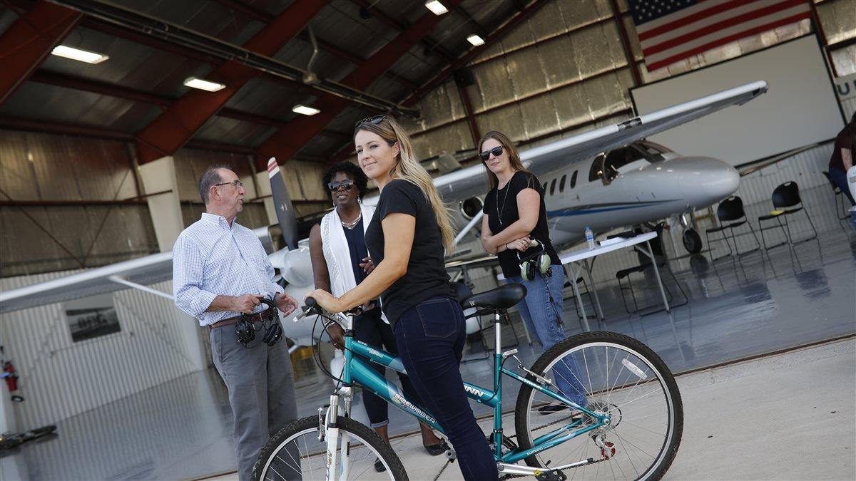 A staged photoshoot at AOPA's NACC with 15-20 "flying club members" interacting in scenarios such as BBQ, flight planning, group watching video, washing airplane, etc.